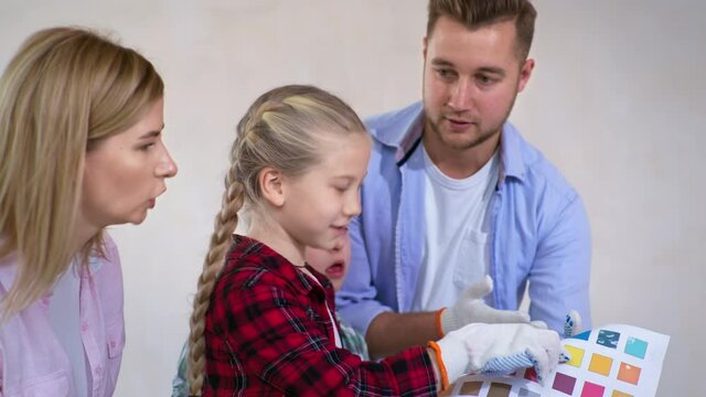 home improvement and design, happy family with kids and down syndrome boy choosing paint from color palette to paint walls during renovation and painting work in room