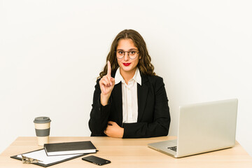 Young caucasian business woman working on her desktop isolated showing number one with finger.