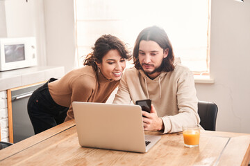 Man and woman looking at smartphone while sitting at table