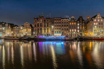 illuminated boat with city at night in Amsterdam.