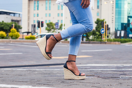 Woman in blue stylish denim jeans and wedge sandals with 1 leg raised in  the city street. Stock Photo | Adobe Stock