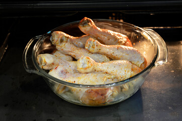 raw, marinated chicken drumsticks are folded into a glass baking dish and placed in the oven