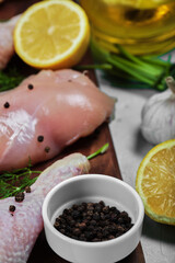 Raw chicken fillet and legs on wooden plate with fresh vegetables. Close up