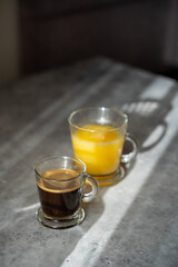 a cup of coffee with glass of orange juice on a table. sunny morning. Gray background