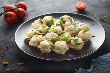 Homemade ready-made dumplings with herbs in a plate on the table. Traditional russian and ukrainian food.