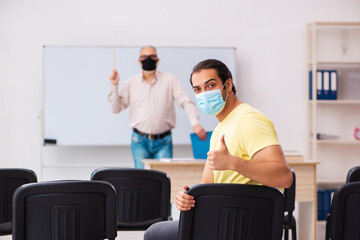 Young male student and experienced teacher in pandemic concept