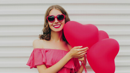 Portrait of happy smiling woman with pink heart shaped balloon on a white background