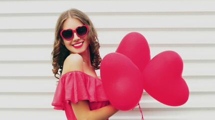 Portrait of happy smiling woman with pink heart shaped balloon on a white background