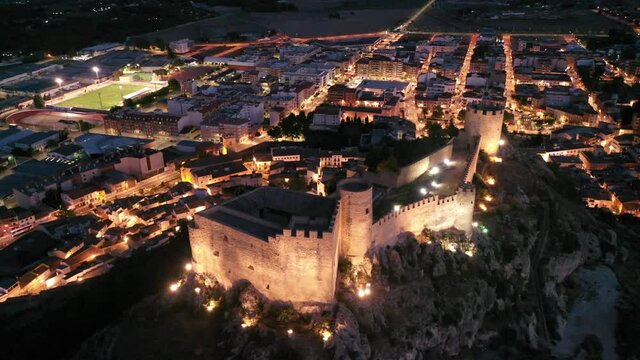 Aerial view of medieval fortified Castalla Castle on top of stone hill on background with townscape in twilight, province of Alicante, Spain