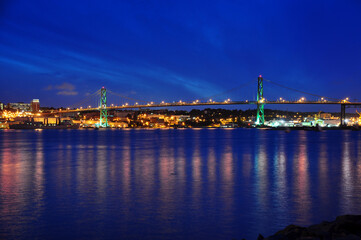 Fototapeta na wymiar Angus L. Macdonald Bridge that connects Halifax to Dartmouth, Nova Scotia. Taken at night with reflections in water
