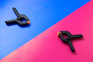 two clamps on opposite sides of the frame. The background is divided diagonally into red and blue