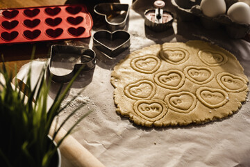 Preparing heart print cookies in raw dough rolled with oklova.