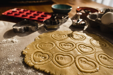 Preparing heart print cookies in raw dough rolled with oklova.