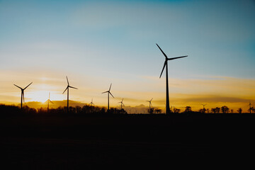 Wind turbines in the field. Wind farm at sunset. Blurred, black silhouette of a wind turbine. Wind energy in Germany