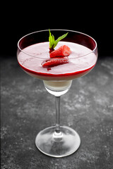 Strawberry panna cotta in a cocktail glass on a dark background