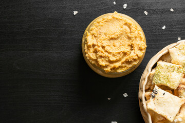 Homemade chickpea hummus and herbal healthy baked wheat vegan vegetarian cracker appetizer food savoury chip snack with black and white sesame and salt