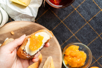 Bread and butter for homemade breakfast with coffee tea milk and organic slide whole wheat rye grain flour brown French  baguette with bio marmalade jam mix with orange passion fruit apricot