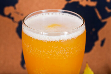 Glass of craft beer with passion fruit on a map background. Close up.