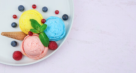 ice cream dessert.
Berry ice cream in a plate with berries, waffle cone and mint on a pink background on the left with space for text on the right, top view close-up.