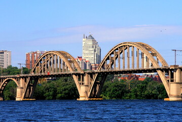 Arched railway bridge over the river, skyscrapers, towers. Spring, summer view of the Dnipro river and the city Dnepropetrovsk, Dnepr, Ukraine.