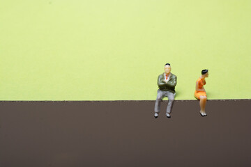 Closeup of the mini-figures of a couple sitting apart not talking after an argument