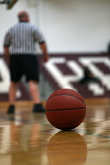 A basketball and referee during a youth basketball game.