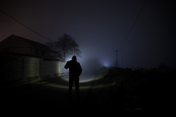 strange light in a dark forest at night. Silhouette of person standing in the dark forest with...