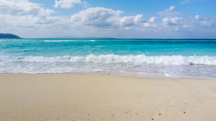 Fototapeta na wymiar アクアブルーの海に白い波しぶきが映えるビーチの写真