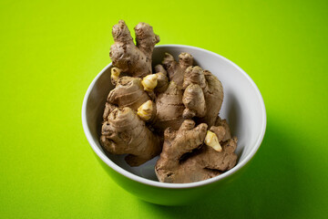 Fresh ginger root on green background