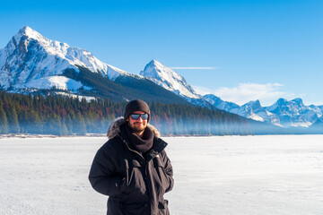 Fototapeta na wymiar Maligne Lake, Canada - december 2020 : young man standing on the frozen lake in winter