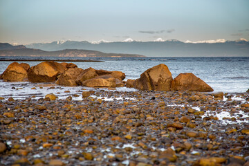 Rock beach ocean and snow cap mountain