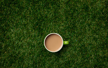 Above view on cup of coffee on green grass.