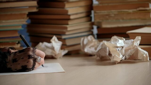 Woman writing essay or love letters on a piece of white paper in library. Closeup of female hands шт gloves with ring, writing notes. Handwritten text