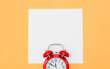 Red alarm clock and white mockup board on yellow background