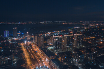 Fototapeta na wymiar Drone view at night, with illuminated streets and dark sky. Beautiful cityscape