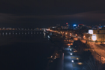 Drone view at night, with illuminated streets and dark sky. Beautiful cityscape