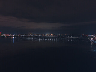 Fototapeta premium Drone view at night, with illuminated streets and dark sky. Beautiful cityscape