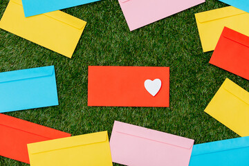 heart shape and envelopes on green grass.