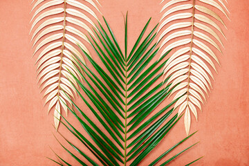 Obraz premium Golden palm branches and green on pink background.