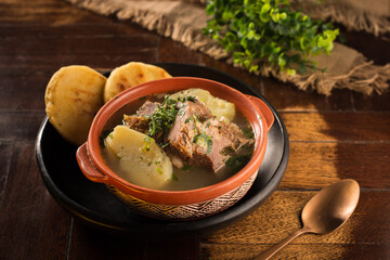 vista cenital Caldo de costilla con papa pastusa arepa  y cilantro en un plato tipico colombiano y una cuchara