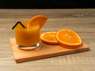 Glass glass with orange juice and orange stand on a wooden gray table