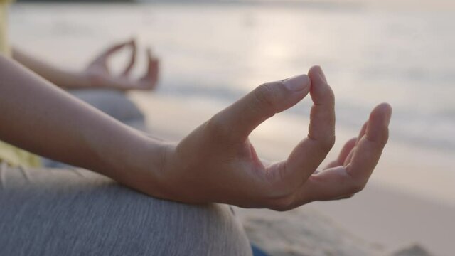 Hand of woman Practicing yoga on a beach in summer sunrise or sunset outdoor. Concept of relaxation and meditation