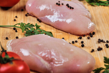 Raw chicken fillets on wooden board with fresh vegetables