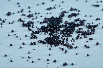 Black caviar scattered on the blue table