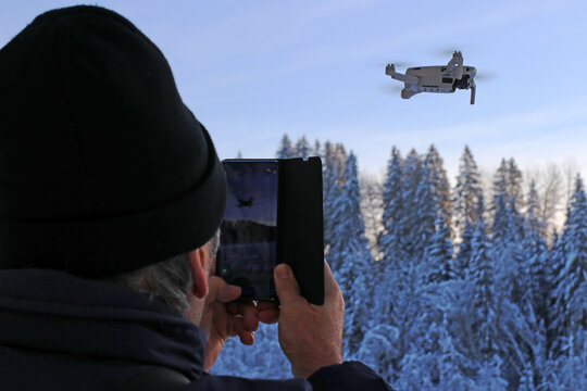 Ein Mann fotografiert mit seinem Smartphone eine fliegende Drohne