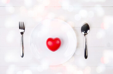 Valentine day, heart shape on dish and utensil with bow for dinner on wooden table, spoon and fork and plate on desk, anniversary and celebration of love, copy space, top view, holiday concept.