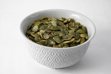 Peeled and roasted pumpkin seeds, in bowl and isolated on white background