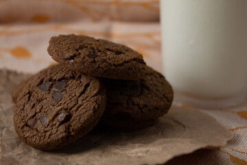 Close up of homemade chocolate chip cookies accompanied by a glass of cold milk