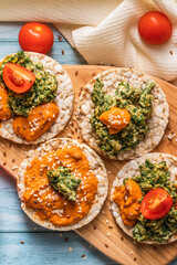 Crispy puffed rice cakes on table with hummus spread spinach with eggs and tomato and vegetables on the table - top view on healthy vegetarian breakfast gluten free