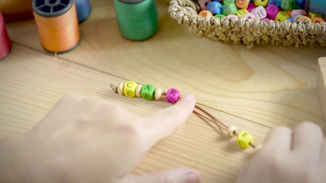 String a bracelet Wooden letter beads of Care word, Close up woman hand string with a colourful Wooden letter beads, mood and tone concept.